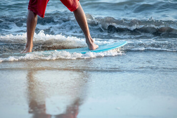 Boy practice to ride skim board on the beach, boy with surfboard on sunset beach, selective focus