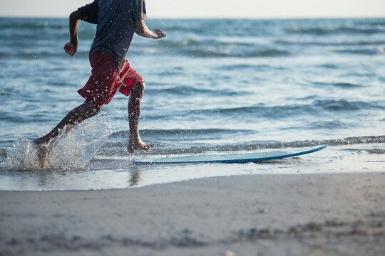 Boy practice to ride skim board on the beach, boy with surfboard on sunset beach, selective focus