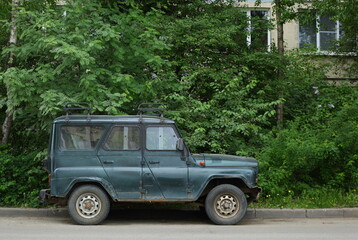 A rusty Russian jeep is parked near a residential building, Podvoysky Street, St. Petersburg, Russia,  May 2023