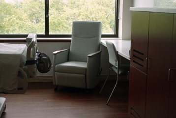 Recliner chair for visitor, patient bed, and desk in a clean hospital room