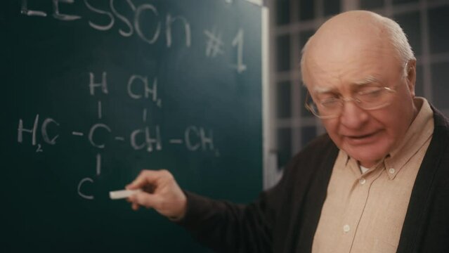 Male professor explaining chemistry equation in class, school teacher, work