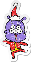 happy hand drawn distressed sticker cartoon of a alien dancing wearing santa hat