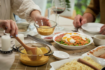 Woman putting pumpkin puree in bowl at dinner table