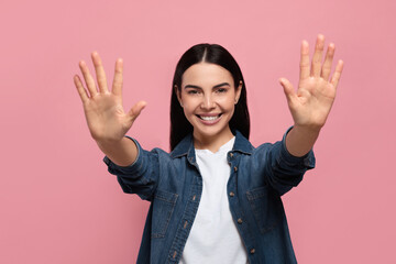 Happy woman giving high five with both hands on pink background