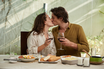 Young couple in love kissing and drinking wine at romantic dinner
