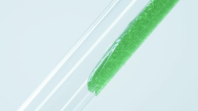 Green gel with air bubbles flows into a glass tube. Substance from marine plants and algae. Biofuel. Nutrient Biomass. Antioxidants and natural ingredients for cosmetics.
