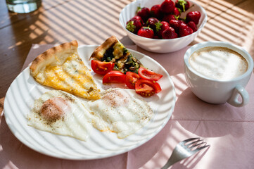 Fried eggs with a slice of pizza and a cup of cappuccino on the table.