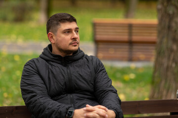 A man is sitting on a bench in the park in autumn