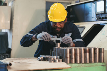Male engineer worker inspecting quality parts of CNC machine in industrial factory, wearing safety...