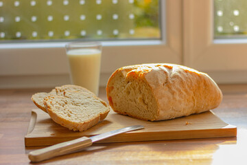 white sliced bread and glass of milk on wooden table in the kitchen