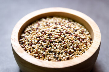 Pile of mixed raw quinoa (Three colors) in wooden bowl on grey background. Quinoa provides protein, dietary fiber, B vitamins, and dietary minerals in rich. Super food of life.