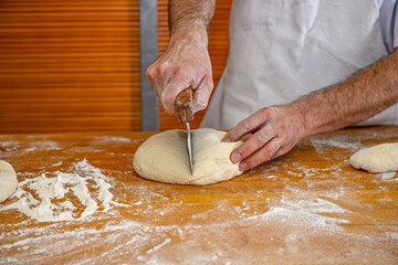 Baker kneading artisan bread in the bakery.
