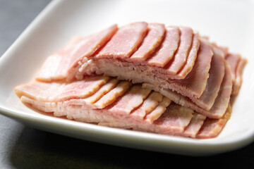 Smoked bacon sliced on white dish.