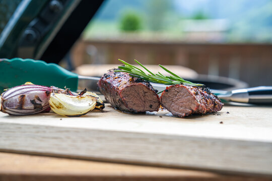 ready to eat, grilled meat from a chamois with rosemary and onions on a wood board