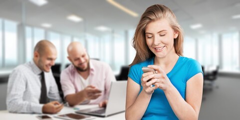 Happy young woman using cellphone in office