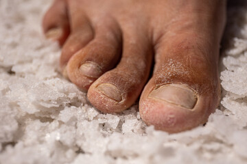 Fototapeta premium foot in pink salt crystals closeup