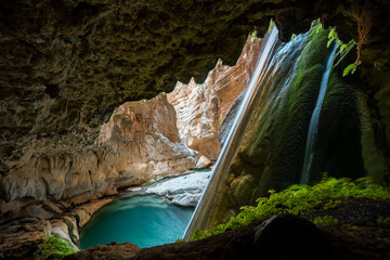 waterfall in huge canyon with azure lake from a cave - Powered by Adobe
