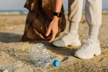 Woman volunteer is collecting plastic waste on the beach to contribute to the effort of keeping...