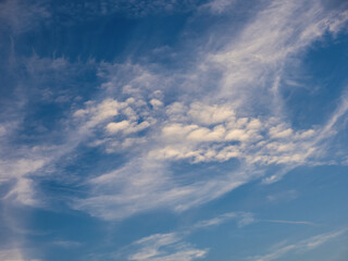 Blue sky with unusual abstract white clouds. Strange dramatic clouds pattern texture.