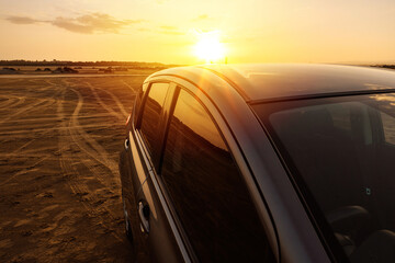 Obraz na płótnie Canvas Beautiful sunset and modern Car Off-roading near the Beach