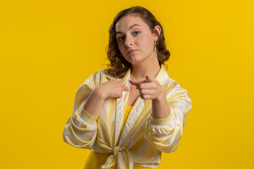 I choose you. Young shocked woman pointing to camera and looking with playful happy expression, making choice, showing direction, choosing. Girl isolated alone on yellow studio background. Lifestyles