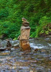 Composition of many river stones among the greenery on a sunny summer day. Selective focus.