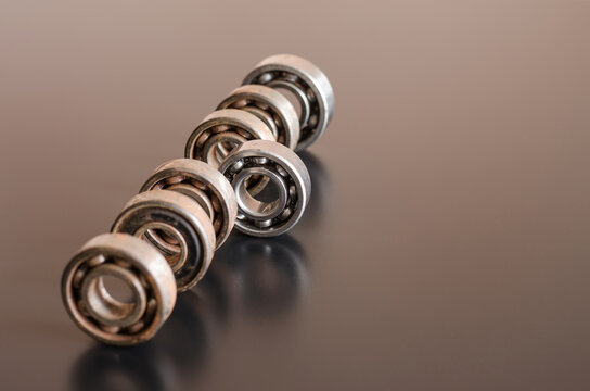 Seven old vintage steel ball bearings lined up in a row on a dark surface, focus on the centrally located bearing version
