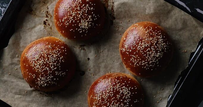 Homemade freshly baked plain golden brown soft hamburger buns with sesame seeds, top view. Homebaking, freshness, bbq concept.