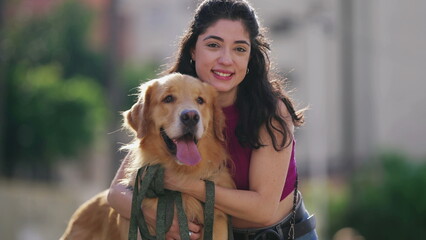 One young woman posing for camera with her Golden Retriever Dog at park during sunny day