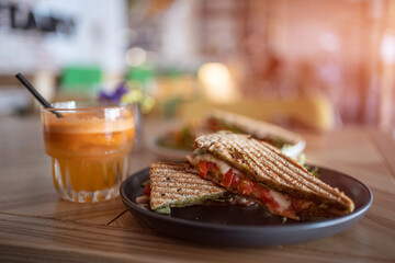 toasted vegetarian sandwich with mozzarella cheese and tomato and orange juice