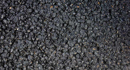 Black texture of asphalt pavement with stones with stones. Black bituminous waterproofing.Bituminous asphalt stones, bitumen chips close-up.