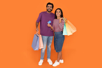 Happy indian lovers holding shopping bags and bank card