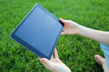 Teen girl  is checking social media holding a tablet outside.