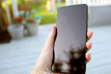 Woman holding smartphone with empty  screen outside.