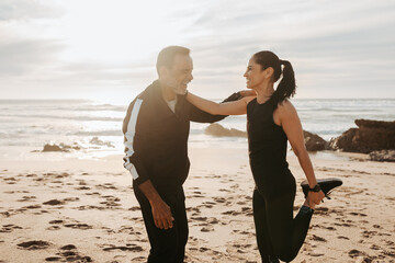 Positive mature european man and woman doing leg exercises, stretching, warm up, enjoy workout together