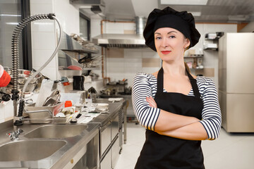 Woman cook. Restaurant kitchen worker. Food business employee. Cafe worker. Girl cook stands with arms crossed. Restaurant owner in chef uniform. Cafe chef looks at camera. Confident woman cook