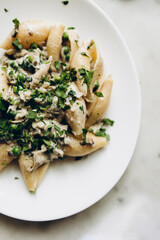 pasta with mushrooms and herbs on a white plate close-up. conchile pasta with white sauce and mushrooms close-up	