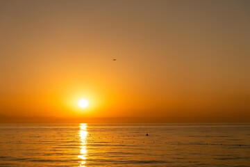 Fototapeta premium Orange dawn on the sea coast, Beldibi, Antalya, Türkiye. The plane at dawn comes in for landing at the airport of Antalya Türkiye. Dawn over Antalya, View from the coast, wallpaper.