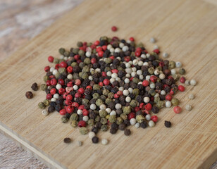 four different peppers on a wooden board