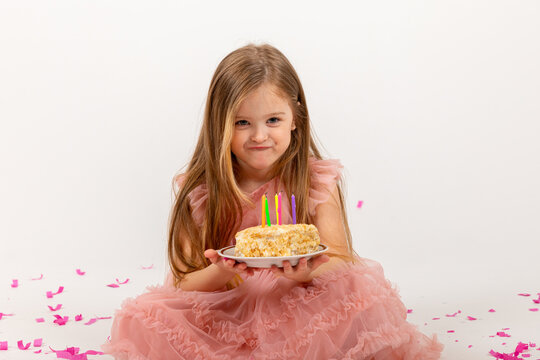 funny little girl in a beautiful dress makes a wish and blows out the candles on the birthday cake. child celebrates his birthday. lifestyle. space for text. High quality photo