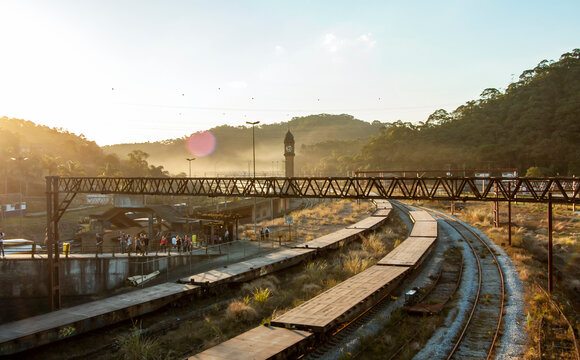 Trens e trilhos na cidade de Paranapiacaba, Santo Andr&eacute;, Brasil, durante o p&ocirc;r-do-sol. Torre do rel&oacute;gio marcando o hor&aacute;rio de partidas em meio aos vag&otilde;es.