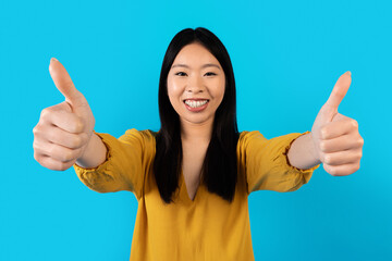 Cheery pretty korean woman showing thumb ups at camera