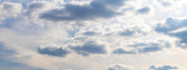 Bright sky with small fluffy clouds illuminated by the sun