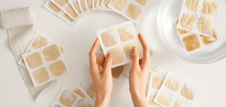 Hands and many mustard plasters on white background, top view