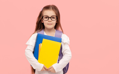 Portrait of a schoolgirl with textbooks and a backpack on a pink background. Back to school