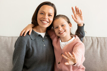 Positive caucasian middle aged daughter and mother wave hands, greeting gesture, say hello in...