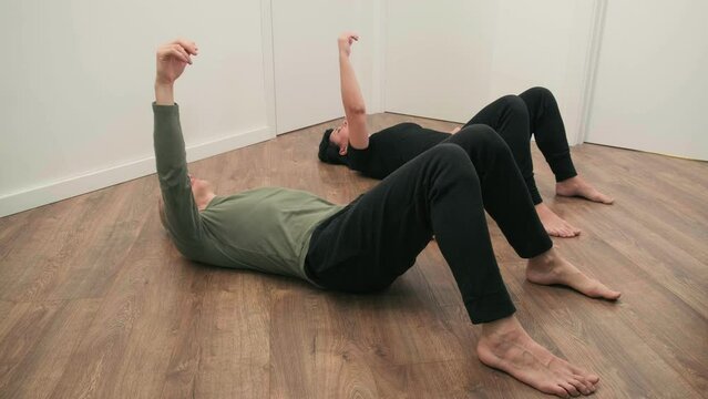 Rehabilitation exercise. Physical therapy concept. Two people laying on the back on the floor with hands and legs up, lymph and blood flow improvement. Feldenkrais method