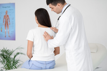 Fototapeta premium Male doctor checking posture of young woman in clinic