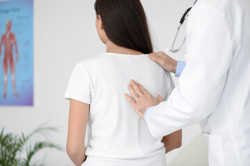 Male doctor checking posture of young woman in clinic