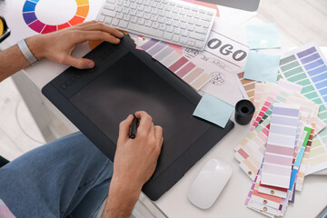 Male graphic designer working with tablet at table in office, closeup